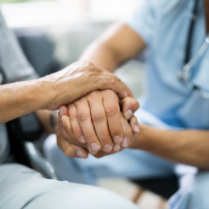 Dignity health: nurse holding elderly loved one's hand.